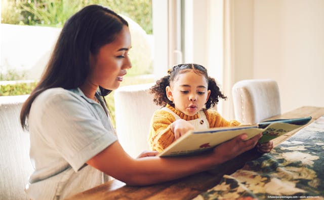 mother reading a book to her daughter with myopia - Image credit: Adobe Stock / Azee/peopleimages.com