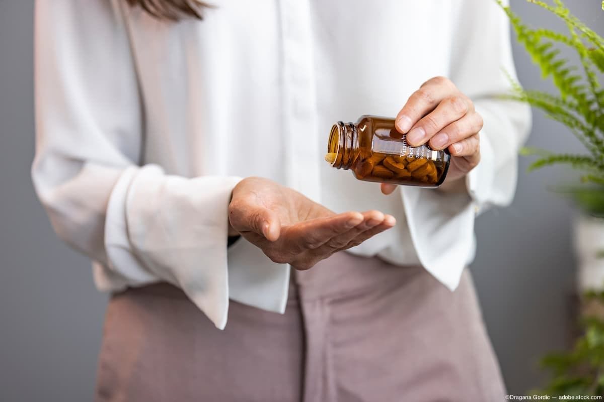 Woman pouring supplements from bottle into hand Image Credit: AdobeStock/DraganaGordic
