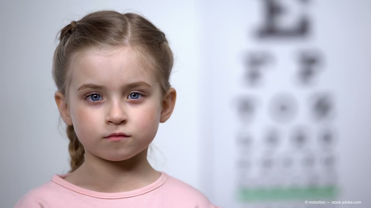 Cute little girl standing on background of visual acuity testing table, optics (Adobe Stock / motortion)