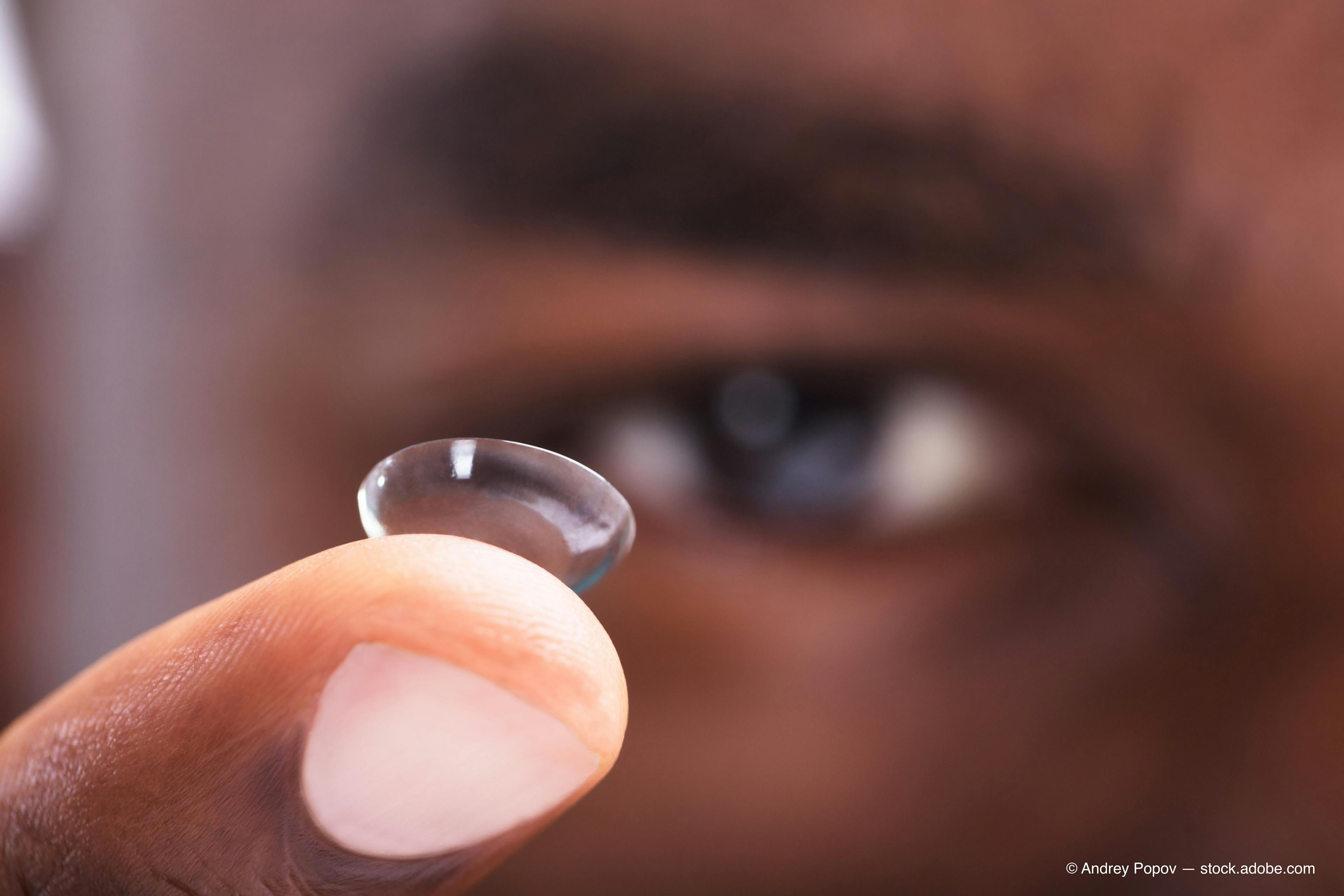 Contact lens on man's finger in front of his eye