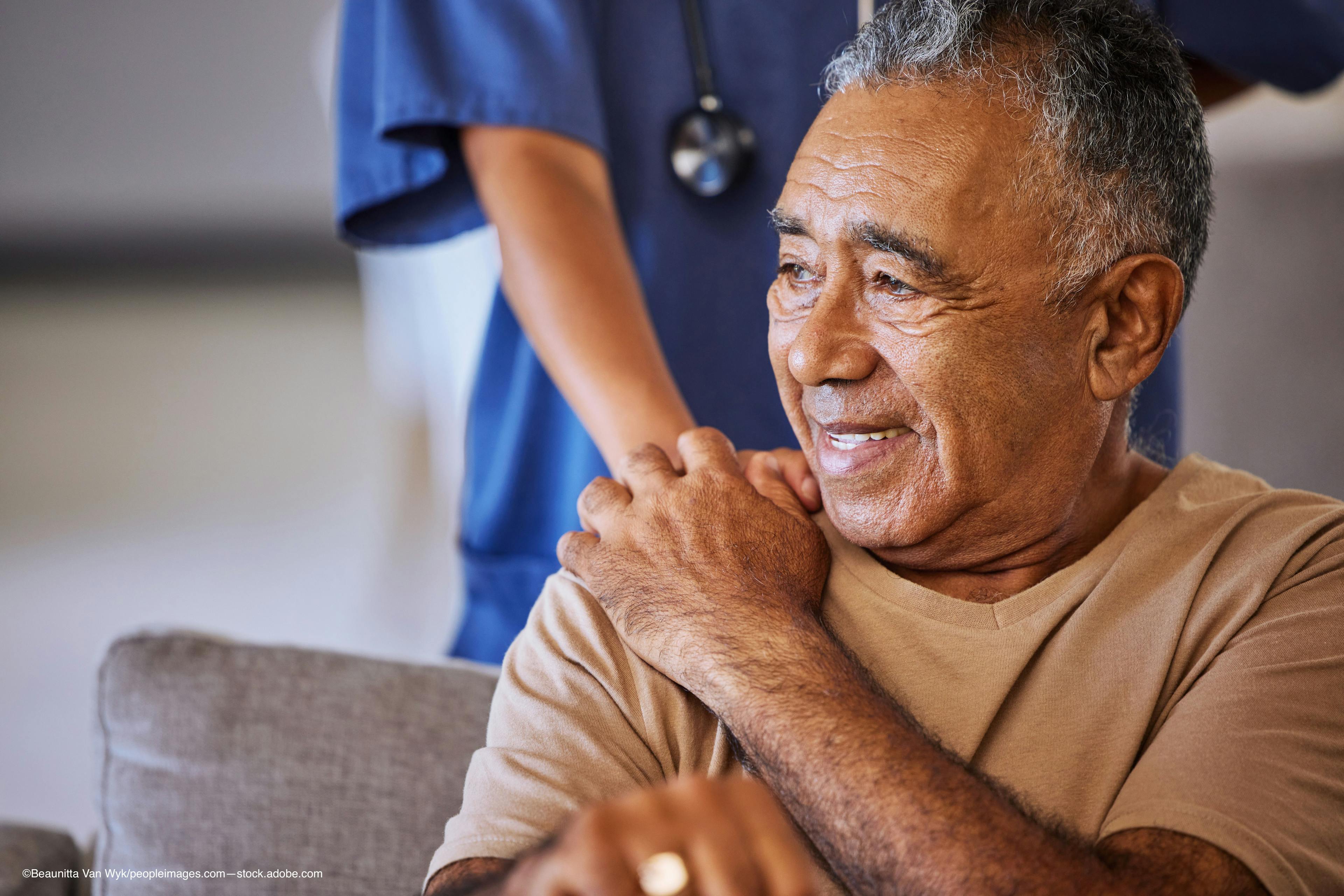 Older man sitting down holding the hand of a physician on his shoulder Image Credit: AdobeStock/BeaunittaVanWyk/peopleimages.com