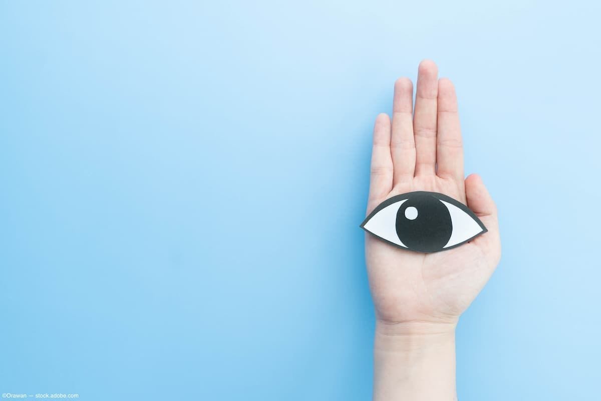 Hand holding paper cutout of eye against blue blackdrop Image Credit: AdobeStock/Orawan