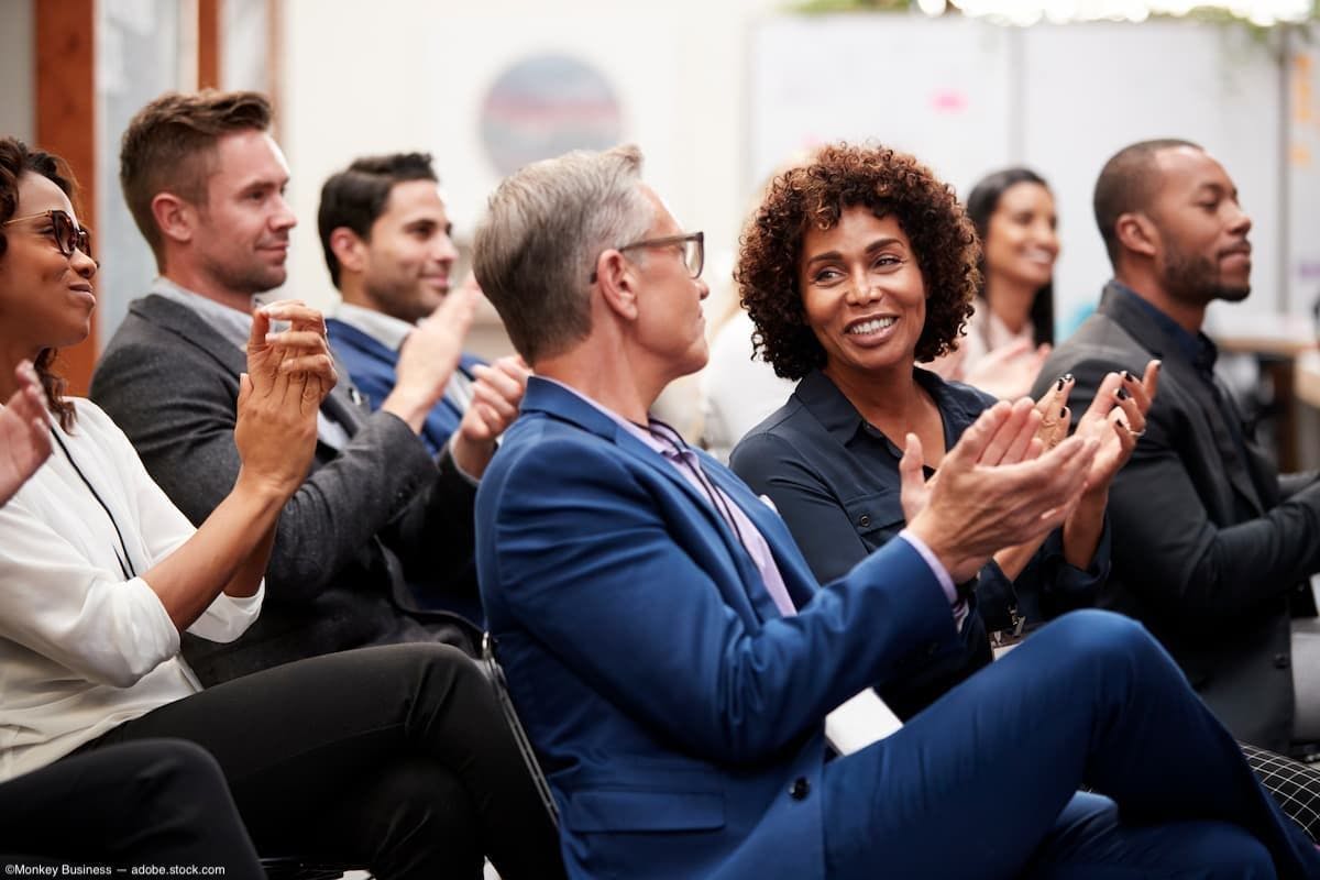 People clapping in audience at conference Image Credit: AdobeStock/MonkeyBusiness