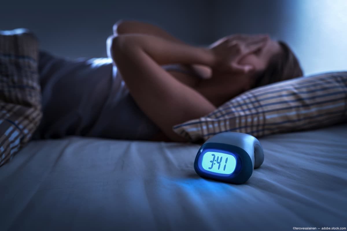 Woman having trouble sleeping with alarm clock on bed Image credit: ©terovesalainen - adobe.stock.com