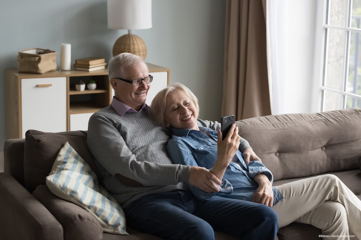 retired couple relaxes at home while looking at smartphone learning about geographic atrophy - Image credit: Adobe Stock / fizkes
