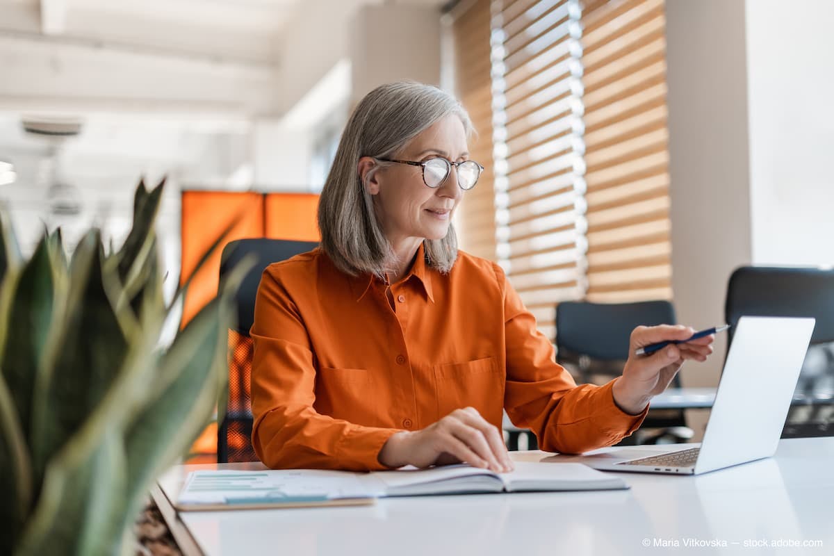 Portrait of beautiful confident senior woman, manager using laptop computer working online sitting in modern office. Business woman wearing stylish eyeglasses checking email. Technology concept (Adobe Stock / Maria Vitkovska)