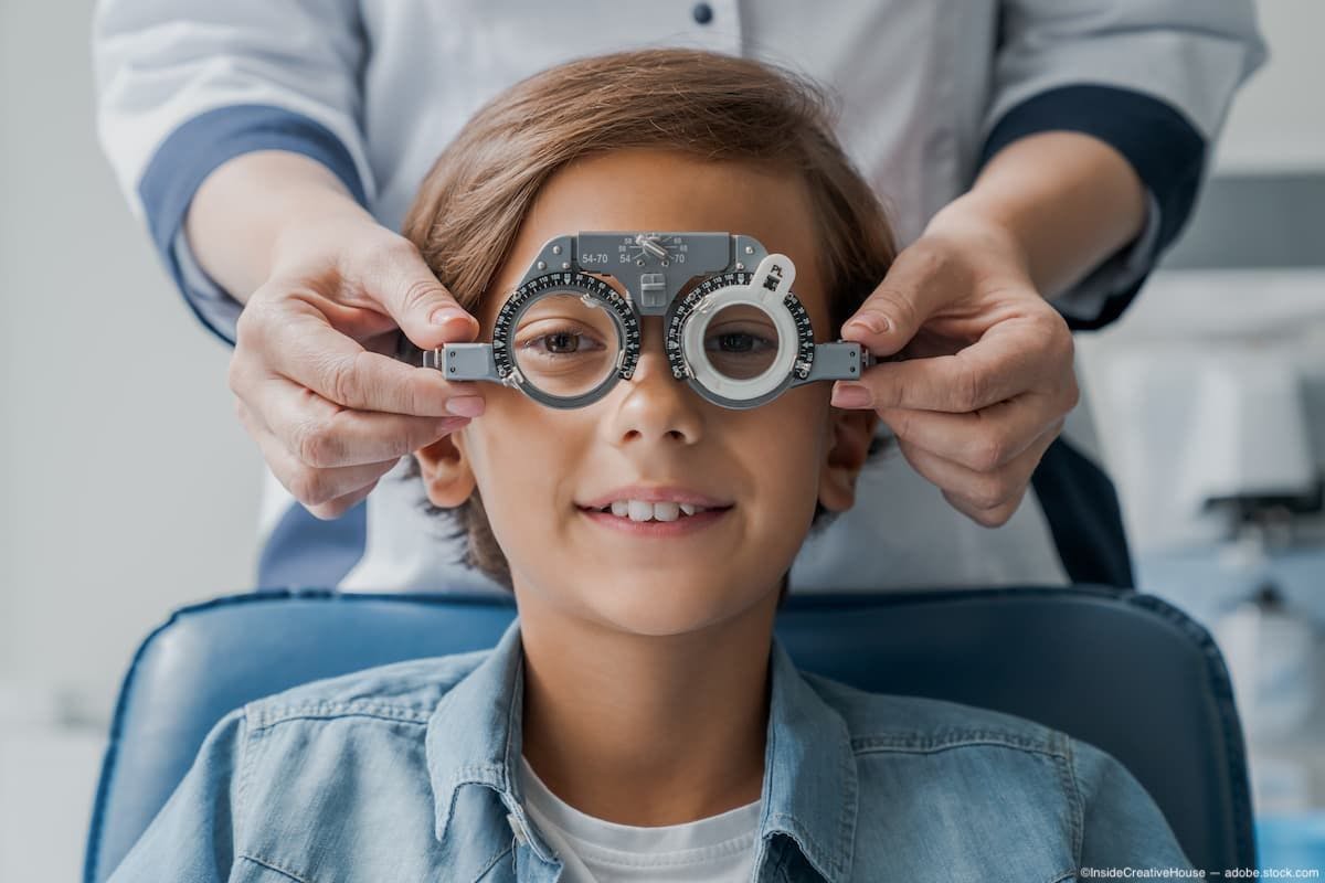 Boy sitting in chair at pediatric office getting vision testing done by physician Image Credit: AdobeStock/InsideCreativeHouse