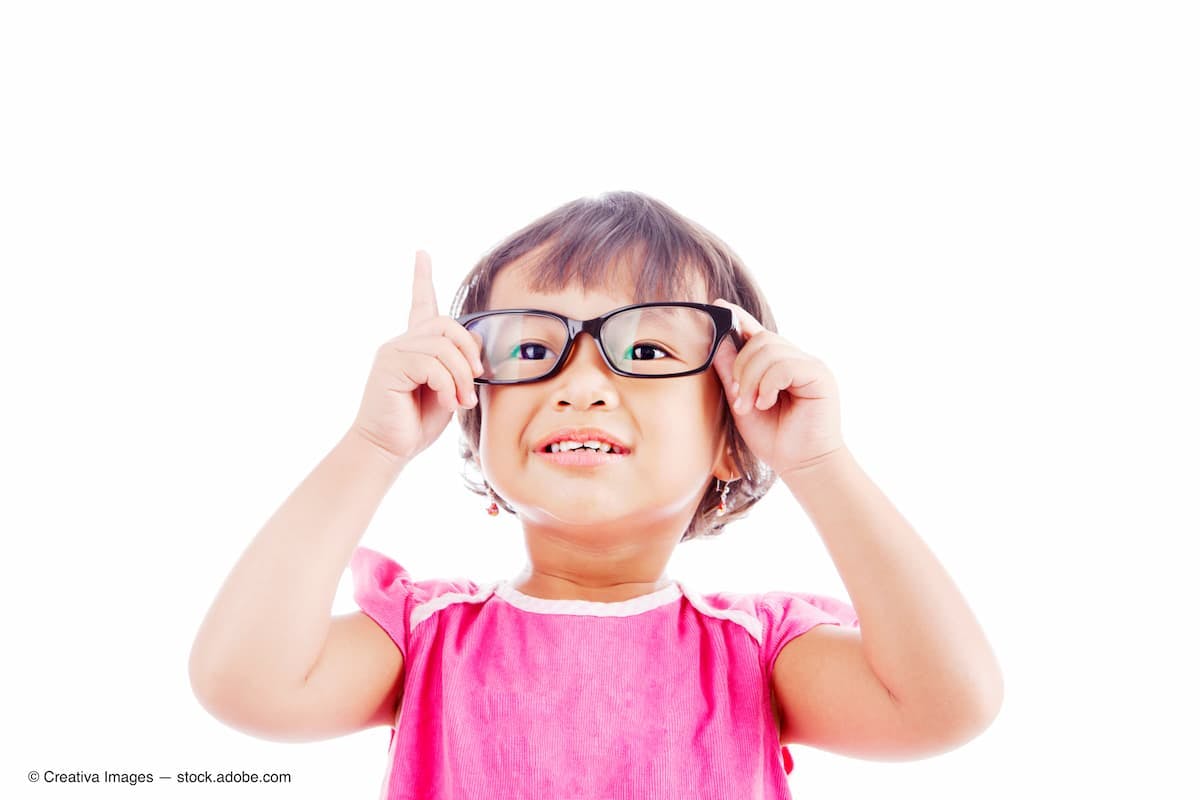 Female preschooler in pink shirt, holding glasses frames up to her face and looking through them (Adobe Stock / Creativa Images)