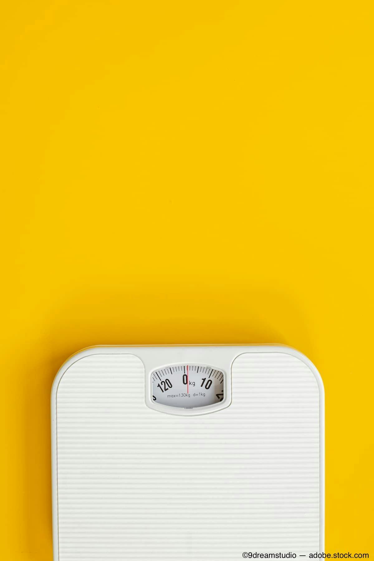 Weight scale on yellow backdrop Image Credit: AdobeStock/9dreamstudio