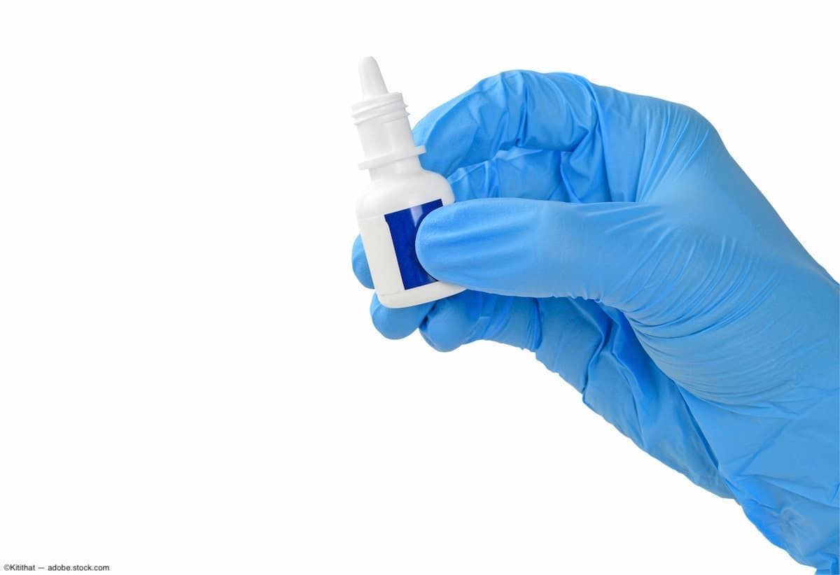 Gloved hand holding eye drop container Image Credit: AdobeStock/Kitithat